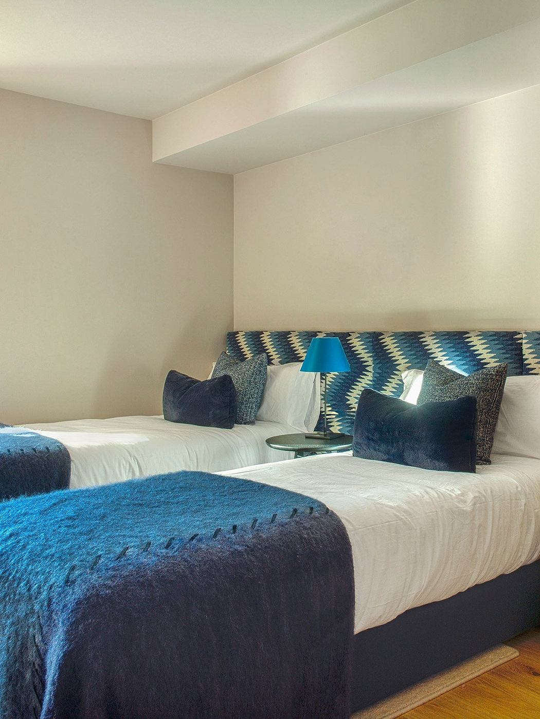 Two twin beds with patterned headboards and plush bedding in a cozy bedroom.