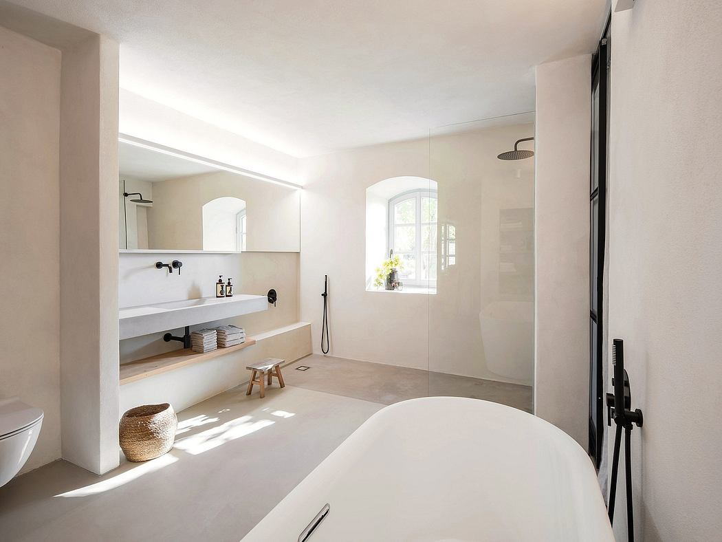 Bright, spacious bathroom with minimalist design, arched window, and freestanding tub.