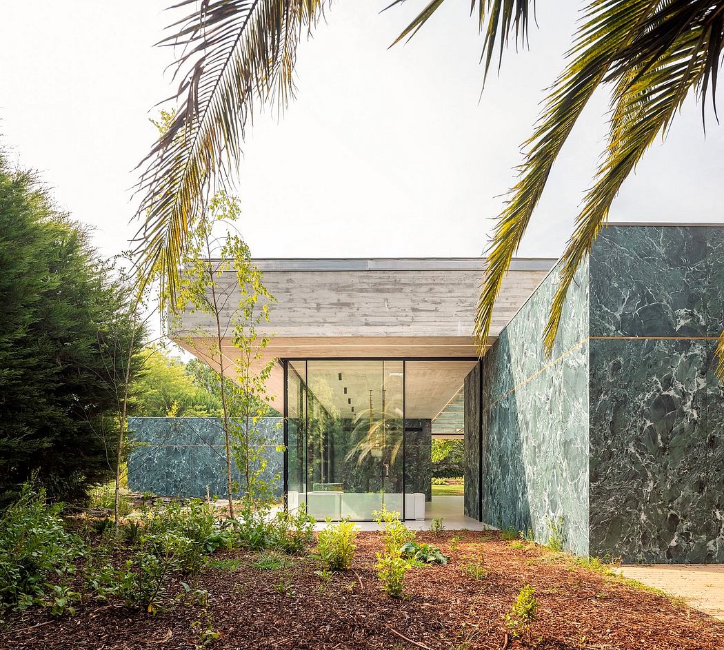 A modern glass and stone structure nestled in a lush tropical landscape.