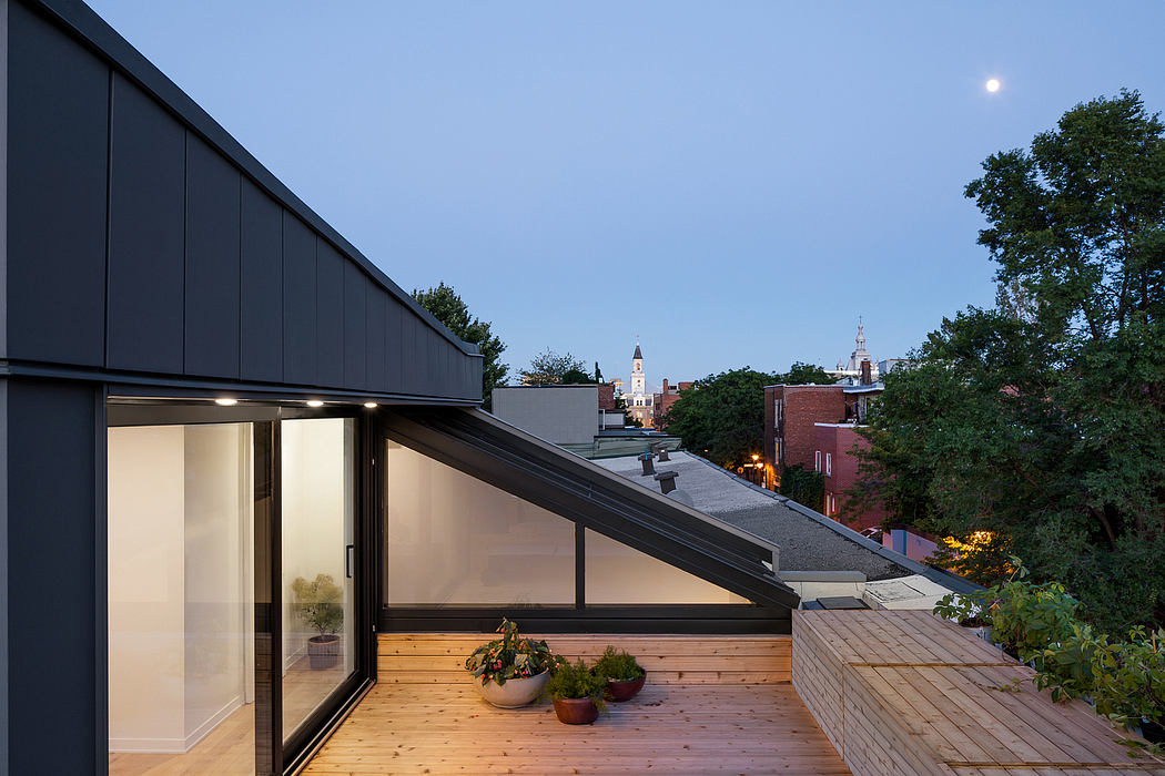 Sleek modern architecture with glass walls, wooden deck, and cityscape view at dusk.