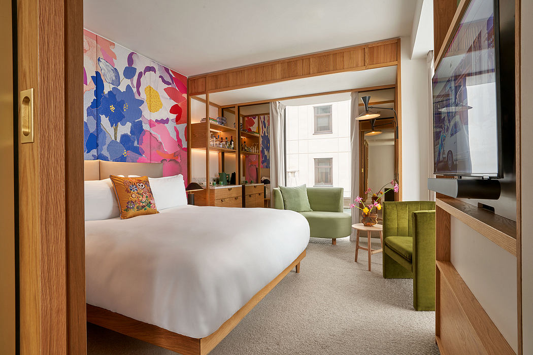 A vibrant, modern hotel room with warm wood accents, colorful artwork, and plush green furnishings.
