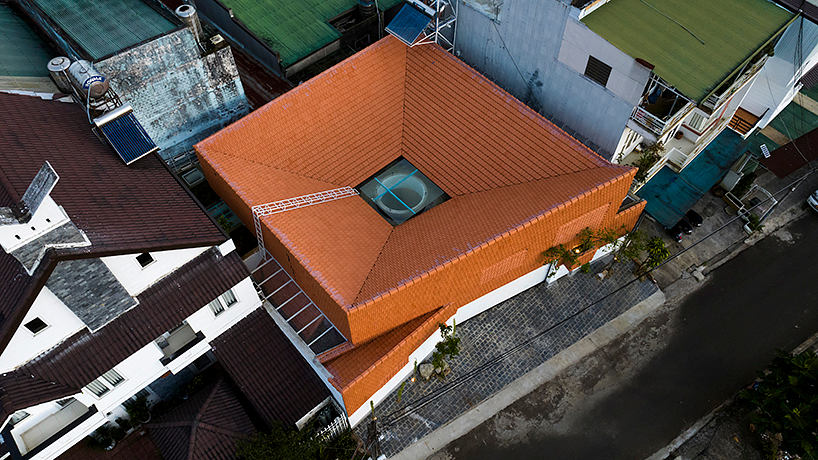 Aerial view of a building with an orange tile roof, surrounded by other structures.