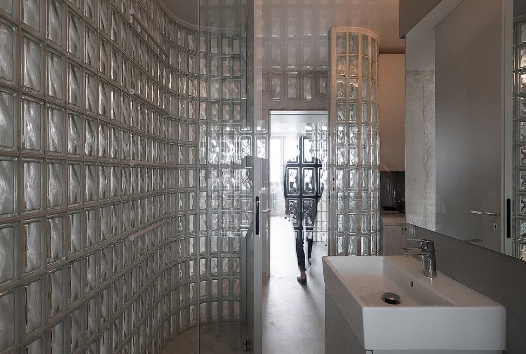A modern bathroom with a curved glass brick wall and a floating sink basin.