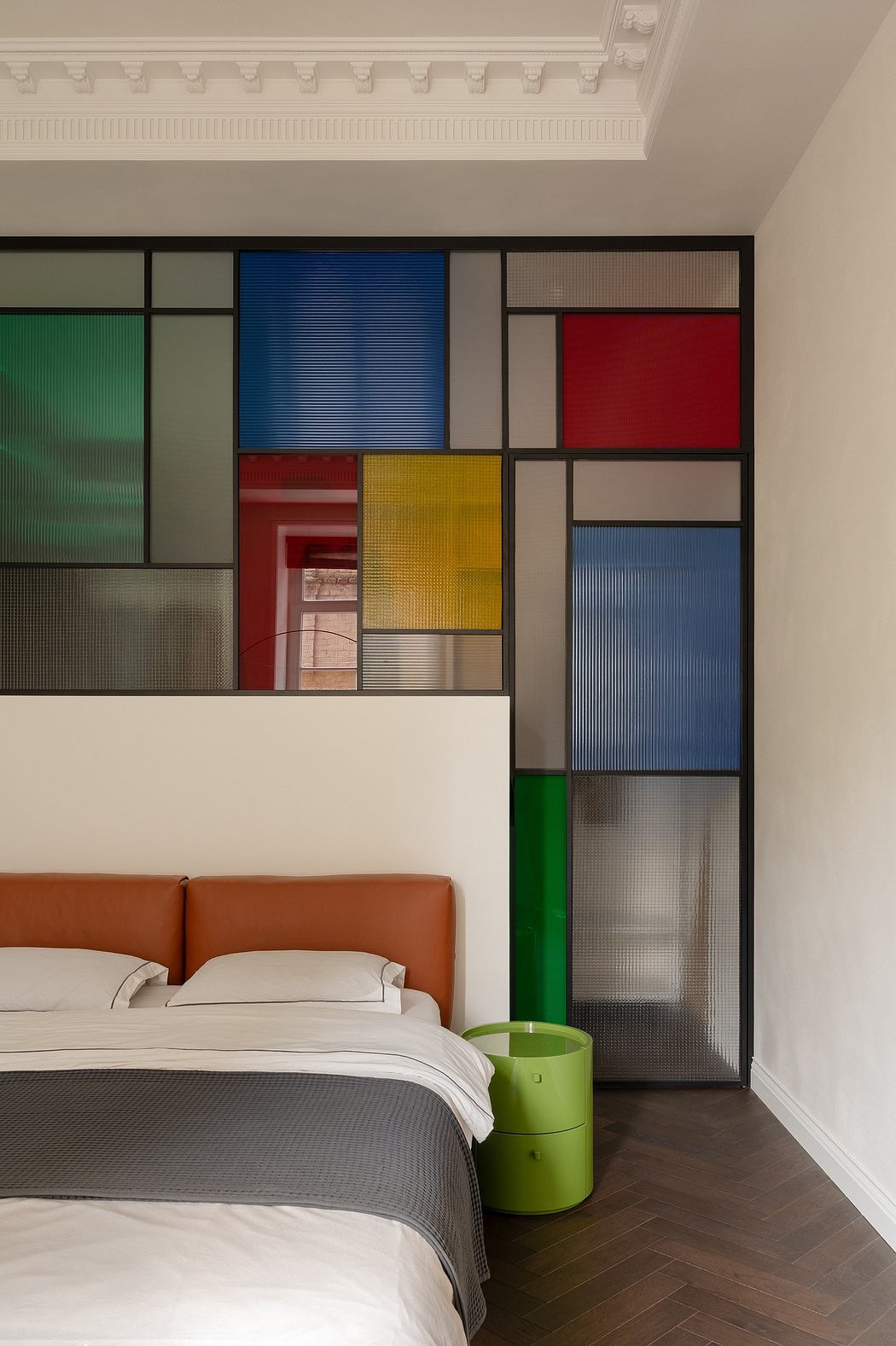 Modern bedroom with vibrant, geometric color-blocked wall panels and sleek furnishings.