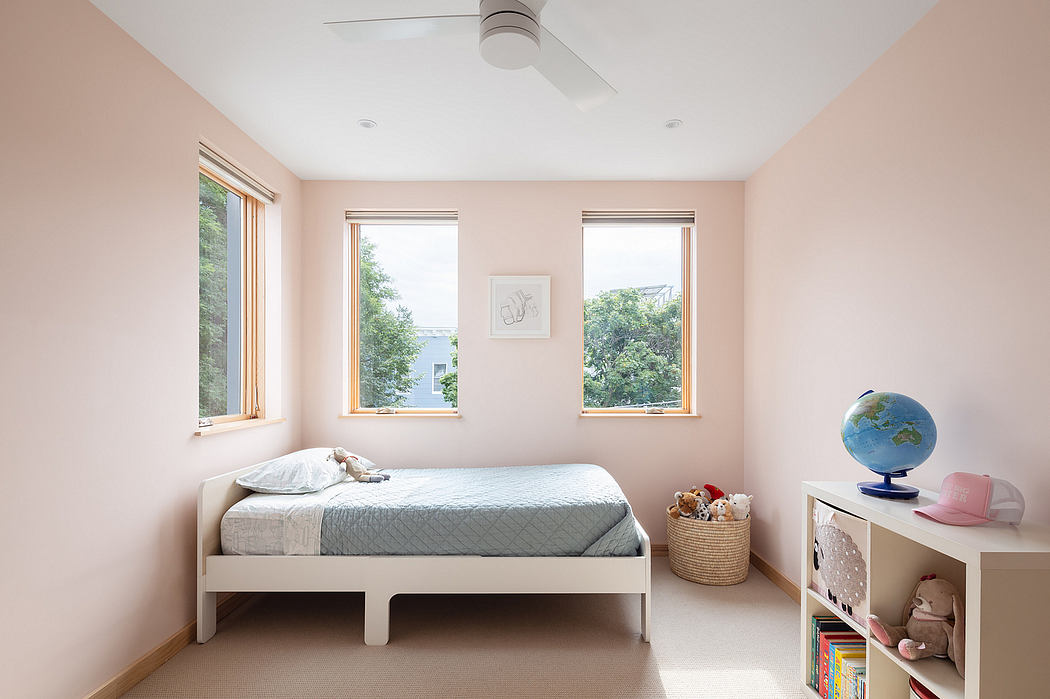 Cozy bedroom with large windows, simple furnishings, and a globe and toys on the shelf.