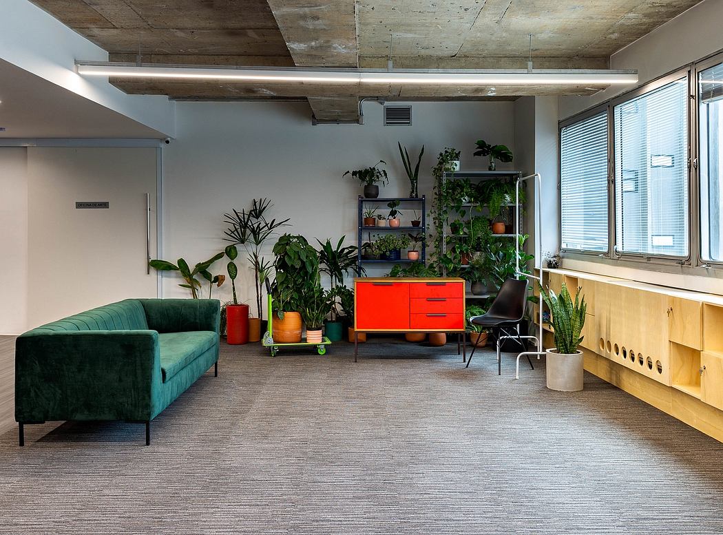 Cozy loft-style office space with concrete ceiling, modern plants, and vibrant furniture.