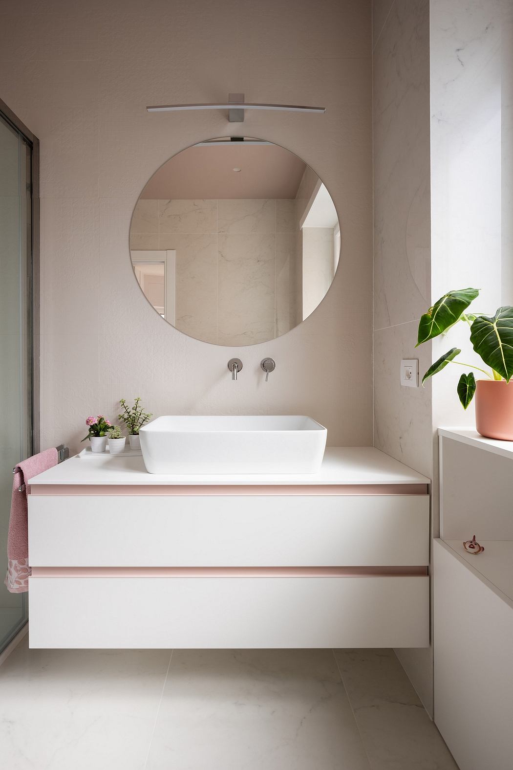 Minimal, modern bathroom design with a round mirror, vessel sink, and potted plant.