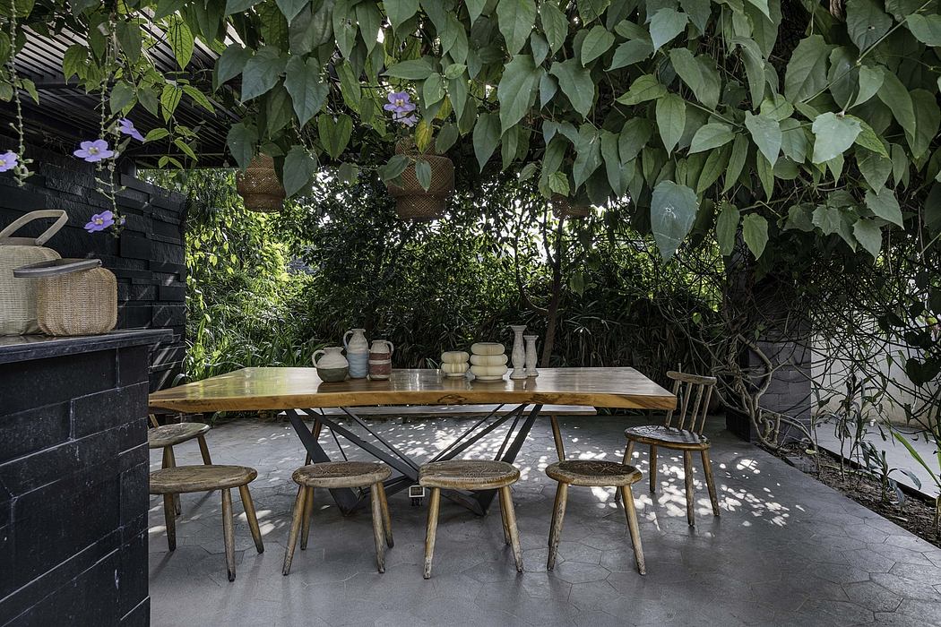 Rustic outdoor dining area amid lush foliage, featuring a wood table and handcrafted stools.