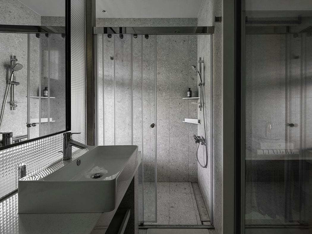 A modern, minimalist bathroom with concrete walls, glass shower enclosure, and a floating vanity.