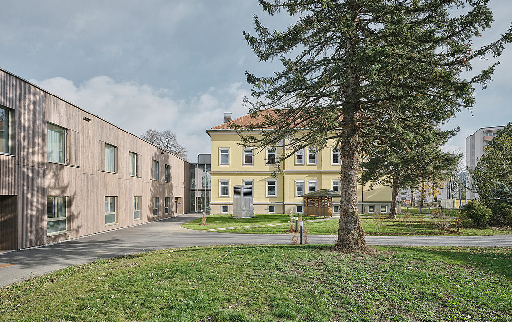 Modern building designs stand in contrast to historic yellow structure, surrounded by lush greenery.