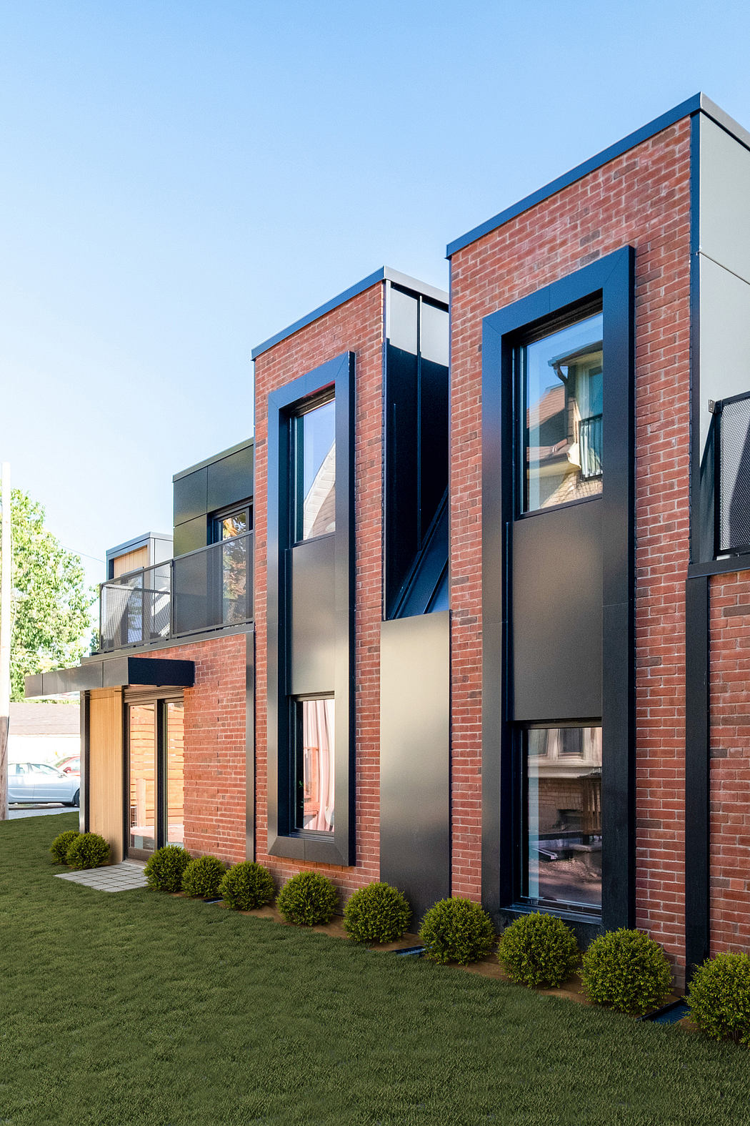 Sleek modern brick and glass building with black window frames and recessed balconies.