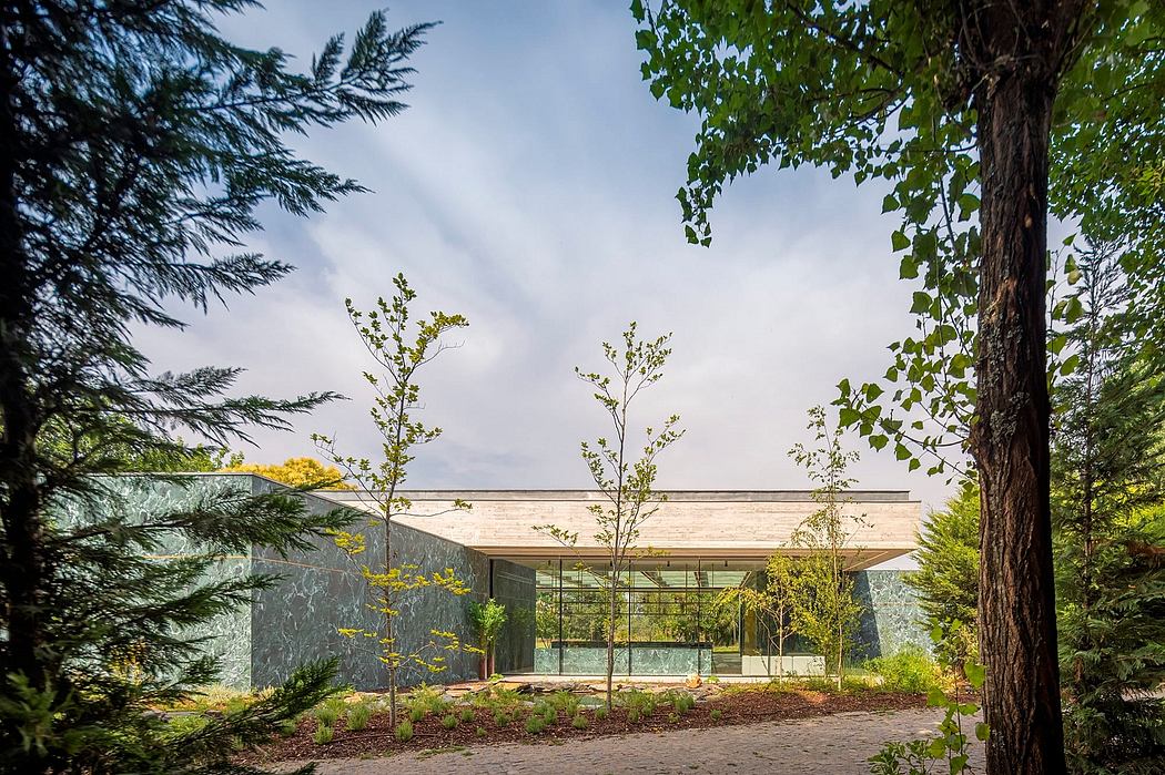 A contemporary glass building with a wood-paneled roof, surrounded by lush foliage.