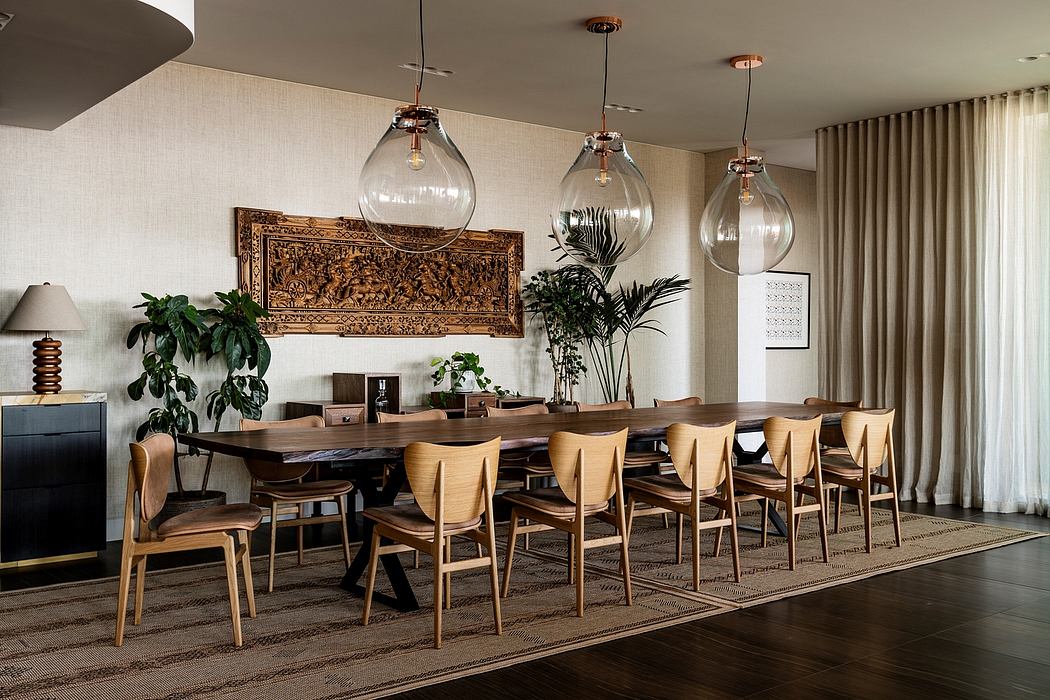 A spacious dining room with a large wooden table, modern pendant lights, and lush plants.