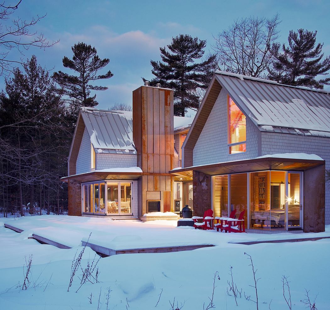 A cozy, modern cabin with a metal roof and expansive windows overlooking a snowy landscape.
