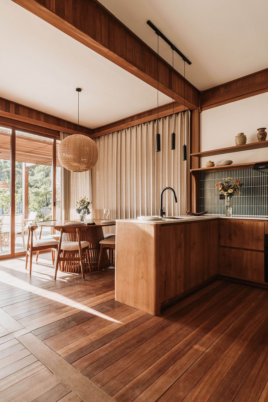 Warm, wooden kitchen and dining area with pendant lighting and floor-to-ceiling windows.