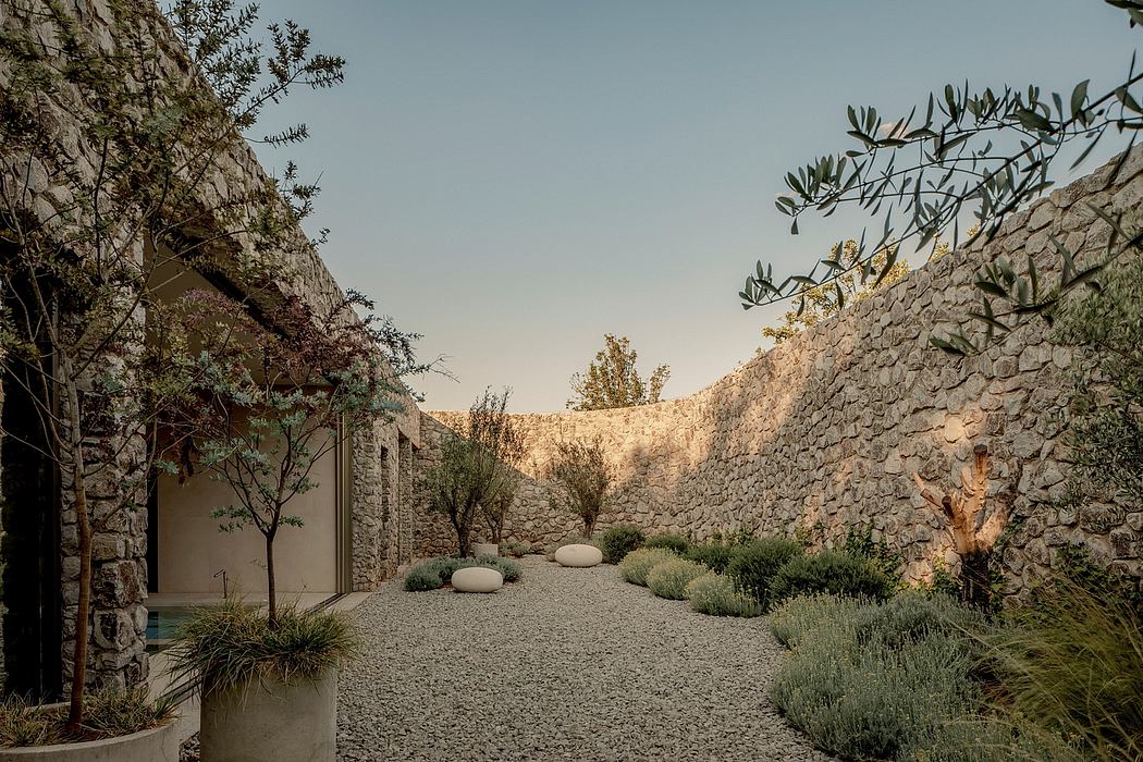 A tranquil stone courtyard with a gravel path, plants, and natural lighting.