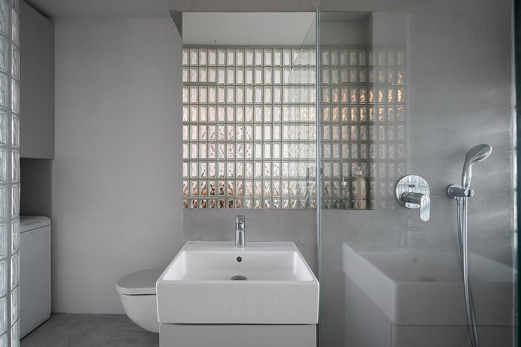 A modern minimalist bathroom with a glass block wall, square sink, and shower.