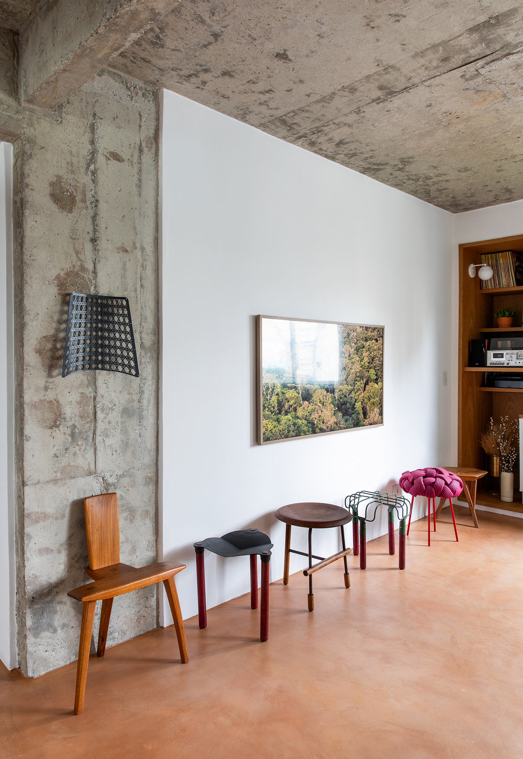 A minimalist interior with concrete walls, wooden furniture, and a framed nature view.