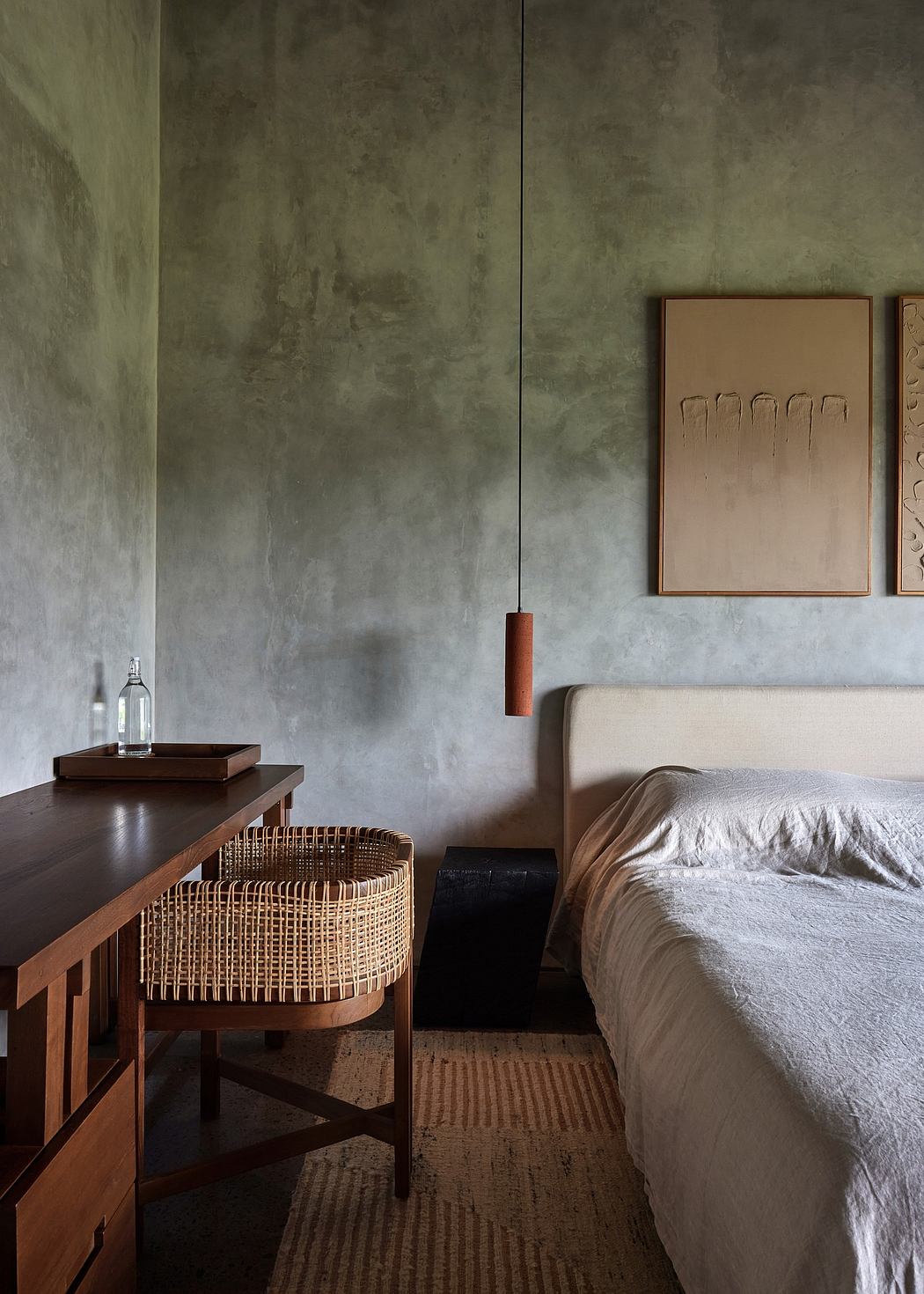 Minimalist bedroom with concrete walls, wooden furniture, and a woven side table.