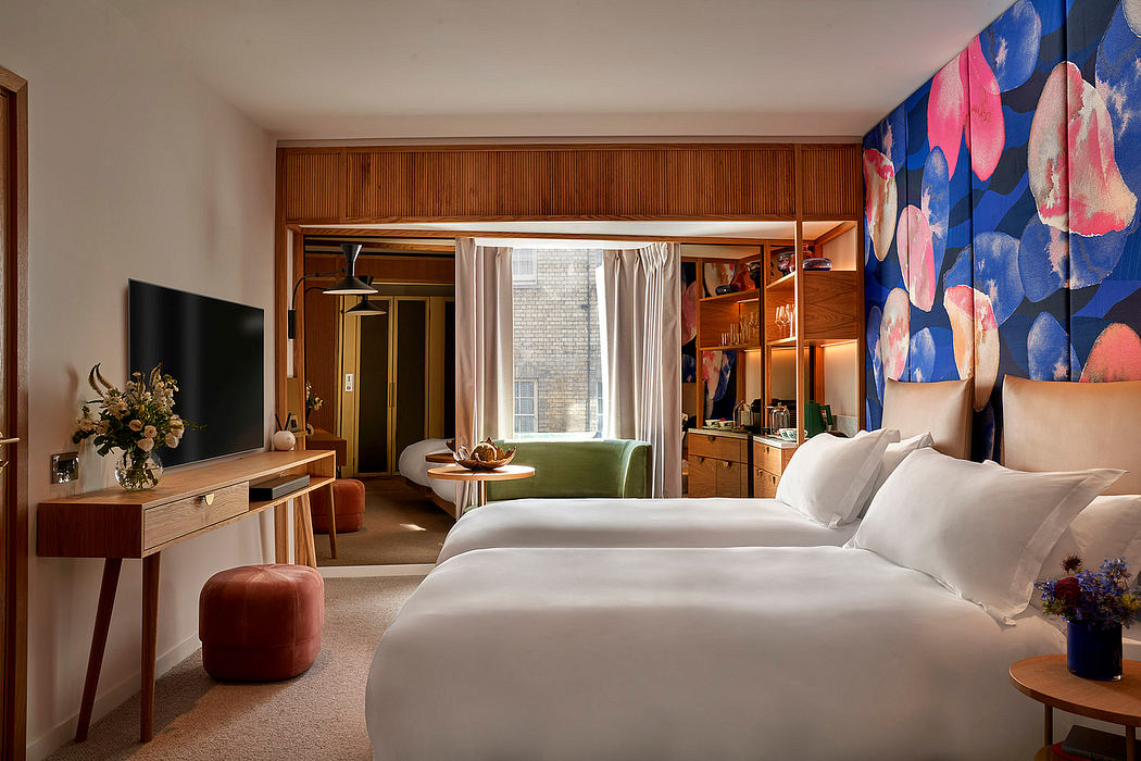 A cozy, modern hotel room with warm wooden furniture, colorful artwork, and a view outside.