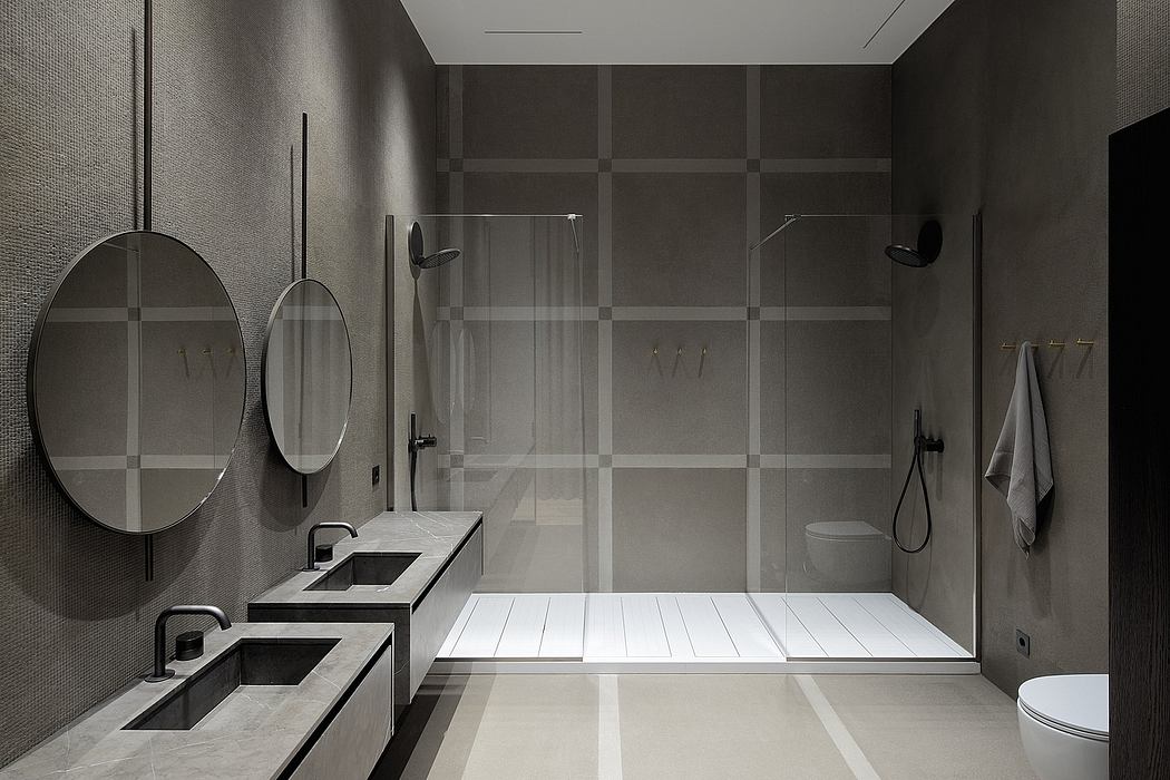Sleek, minimalist bathroom with dark tile, dual vanities, and a spacious shower enclosure.