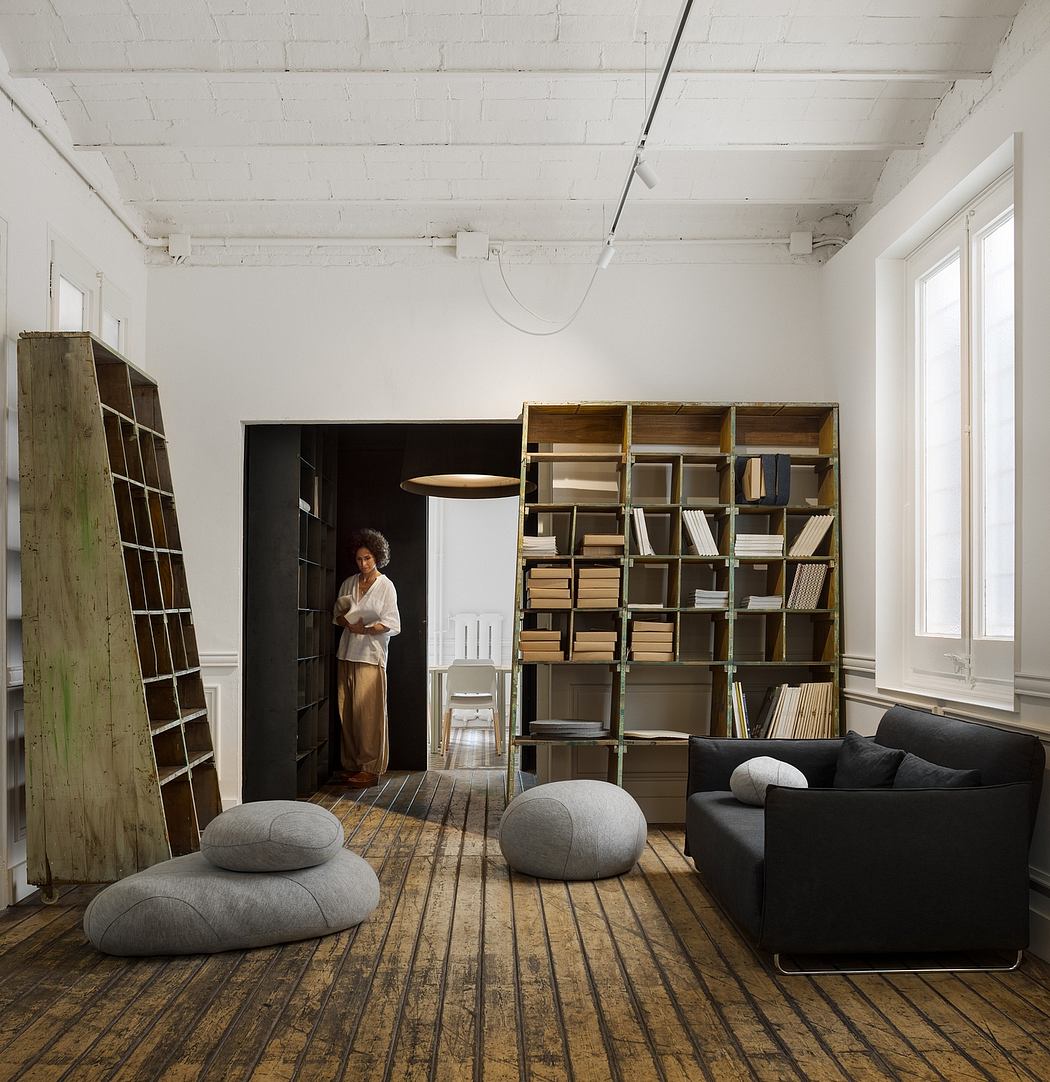 A cozy, minimalist living space with a large bookshelf, comfy seating, and natural lighting.