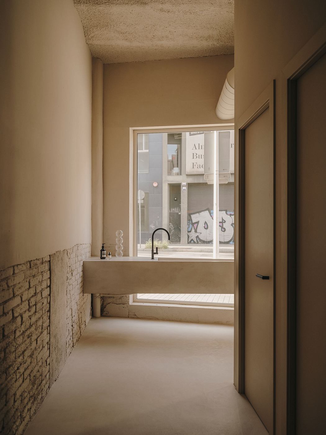 The image shows a minimalist bathroom design with a concrete sink and exposed brick walls, creating a stylish and modern aesthetic.