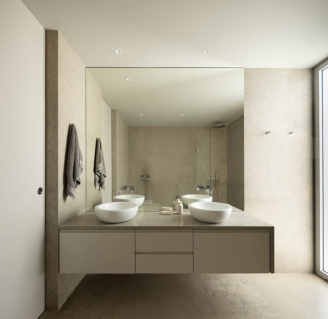 A minimalist bathroom with a sleek vanity, dual sinks, and recessed lighting.