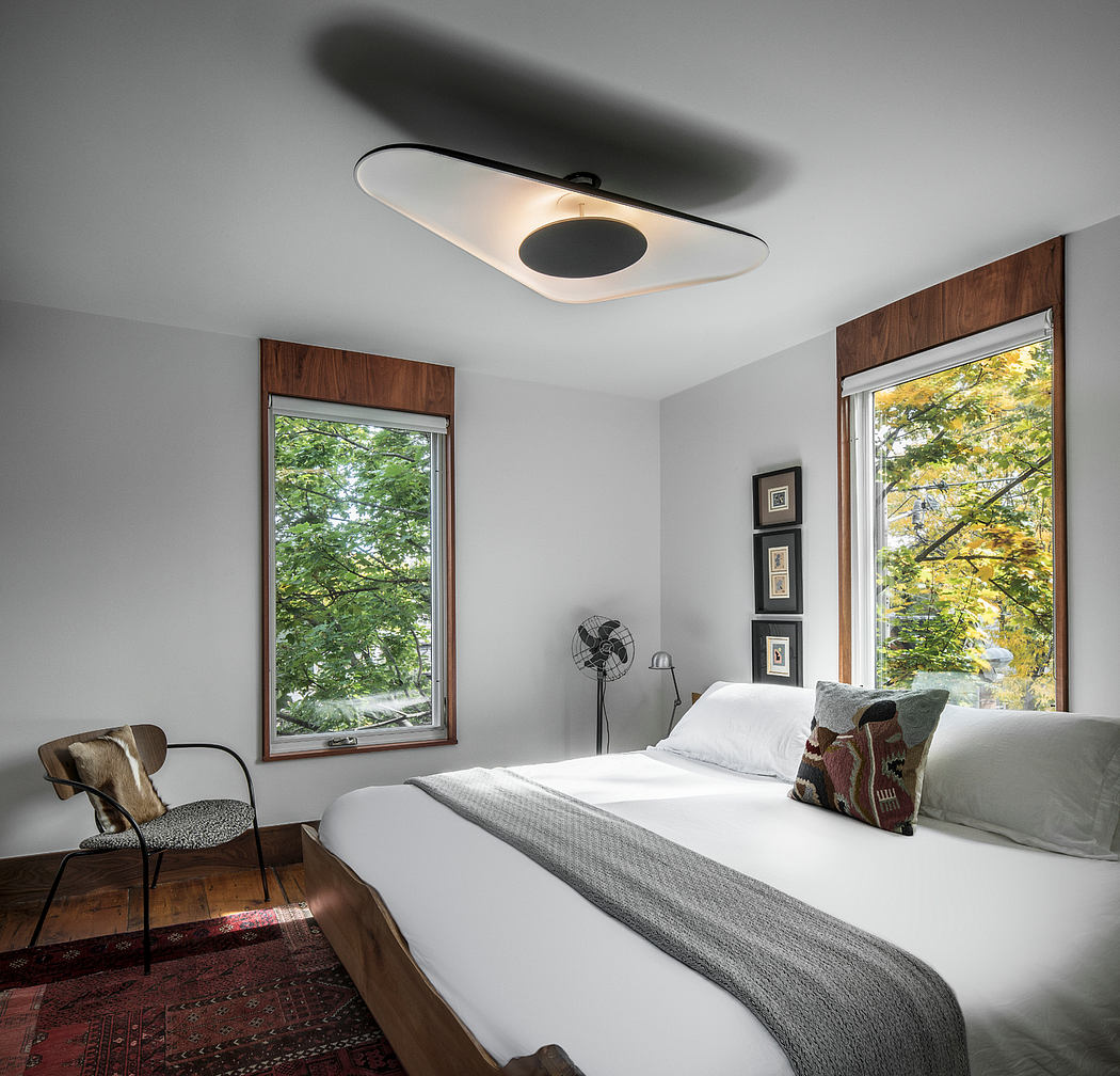 Cozy bedroom with large windows overlooking a lush, forested landscape.