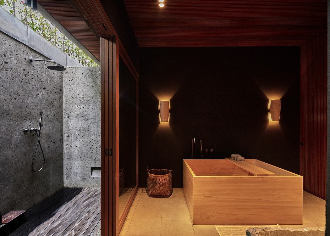 A modern and rustic bathroom with a large wooden soaking tub, stone walls, and elegant lighting.
