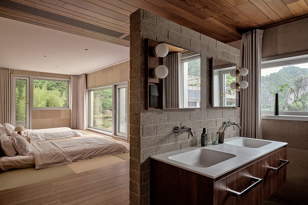 Spacious modern bedroom with stone feature wall, open bathroom area, and panoramic views.