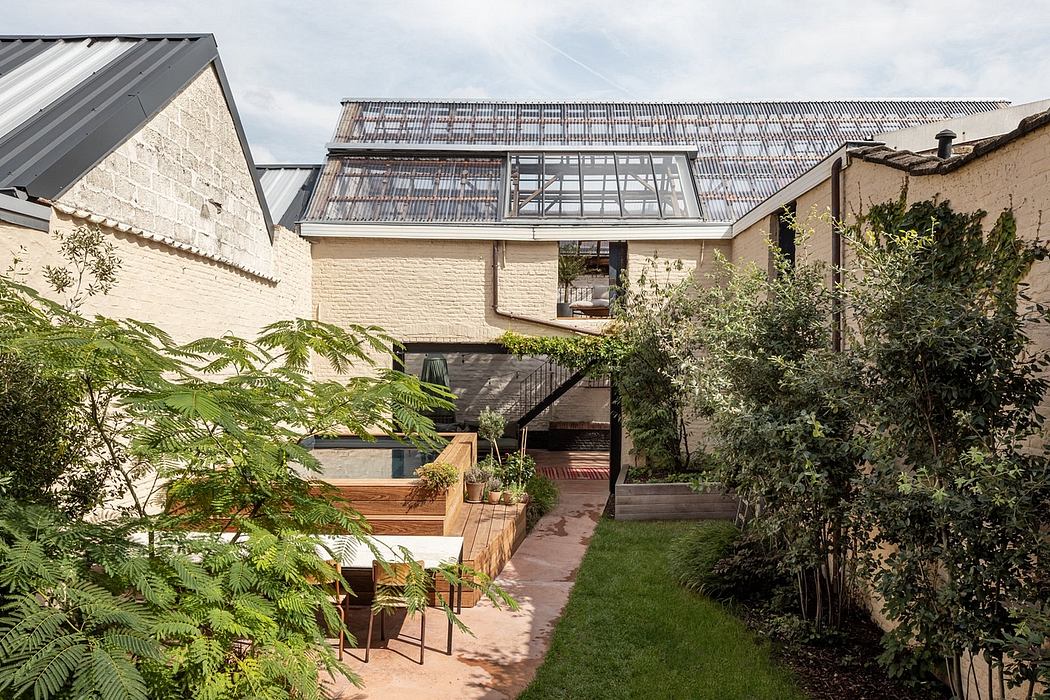 A modern home with a wooden deck, glass walls, and a lush garden in the foreground.