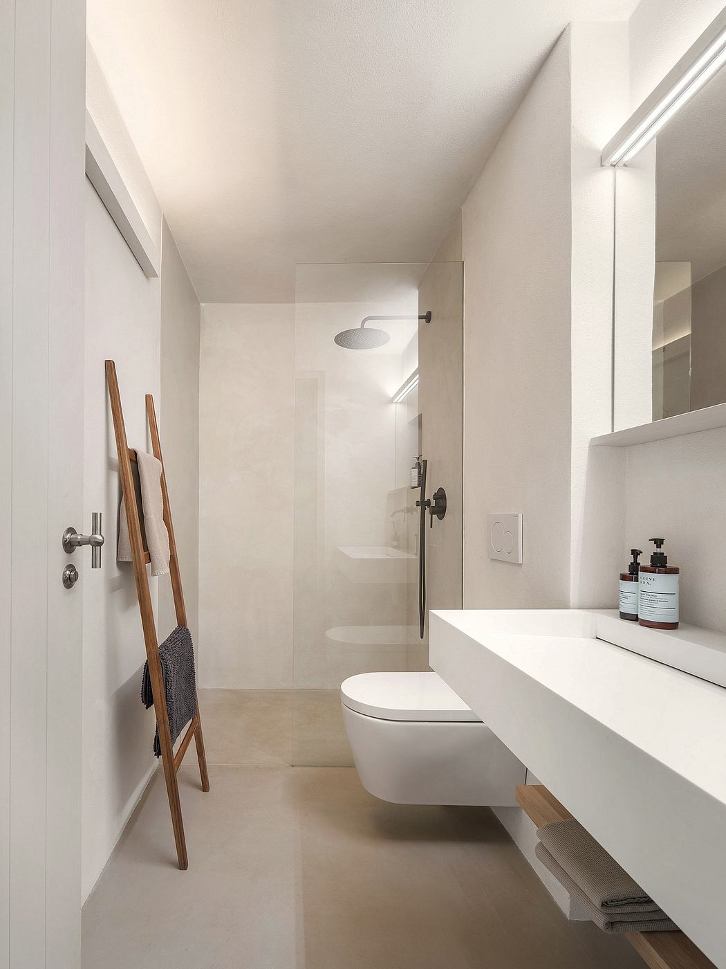 A modern, minimalist bathroom with a sleek white vanity, toilet, and shower enclosure.