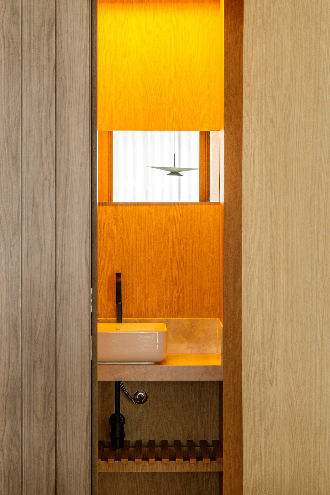 Warm, wooden interior design with glowing orange panels, recessed shelving, and minimalist decor.