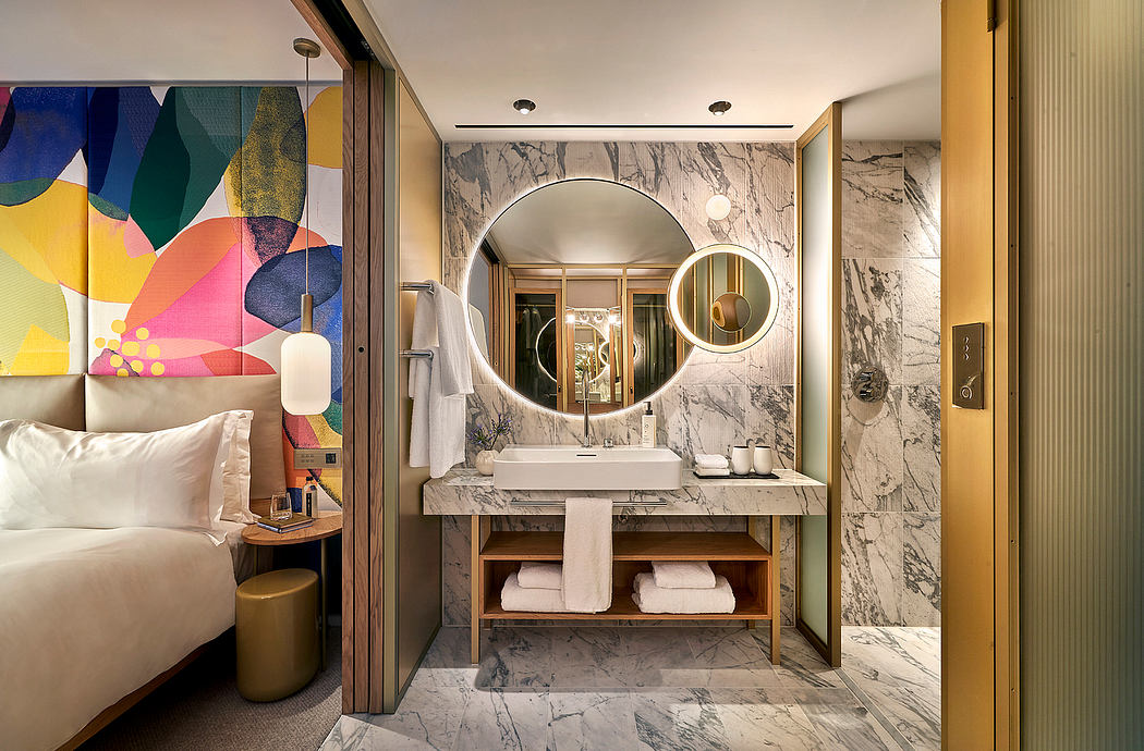 Spacious bathroom with modern marble countertop, circular mirrors, and vibrant wall art.