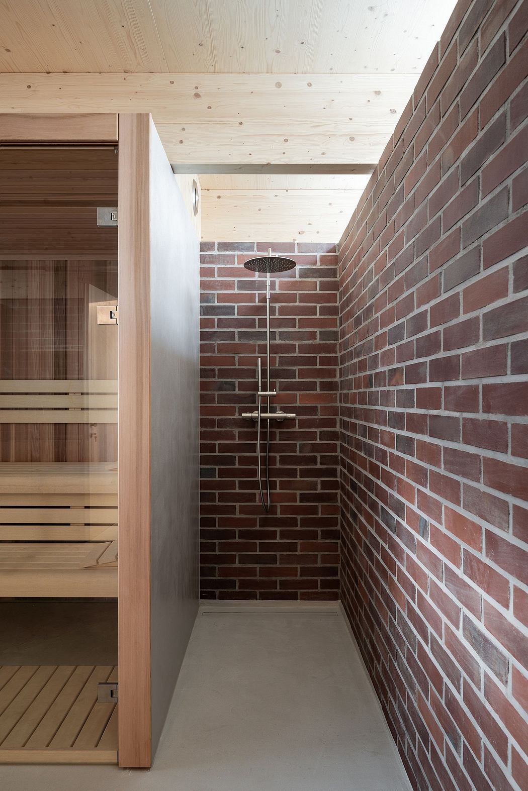 A cozy sauna with a rustic brick wall, wooden details, and a modern shower fixture.