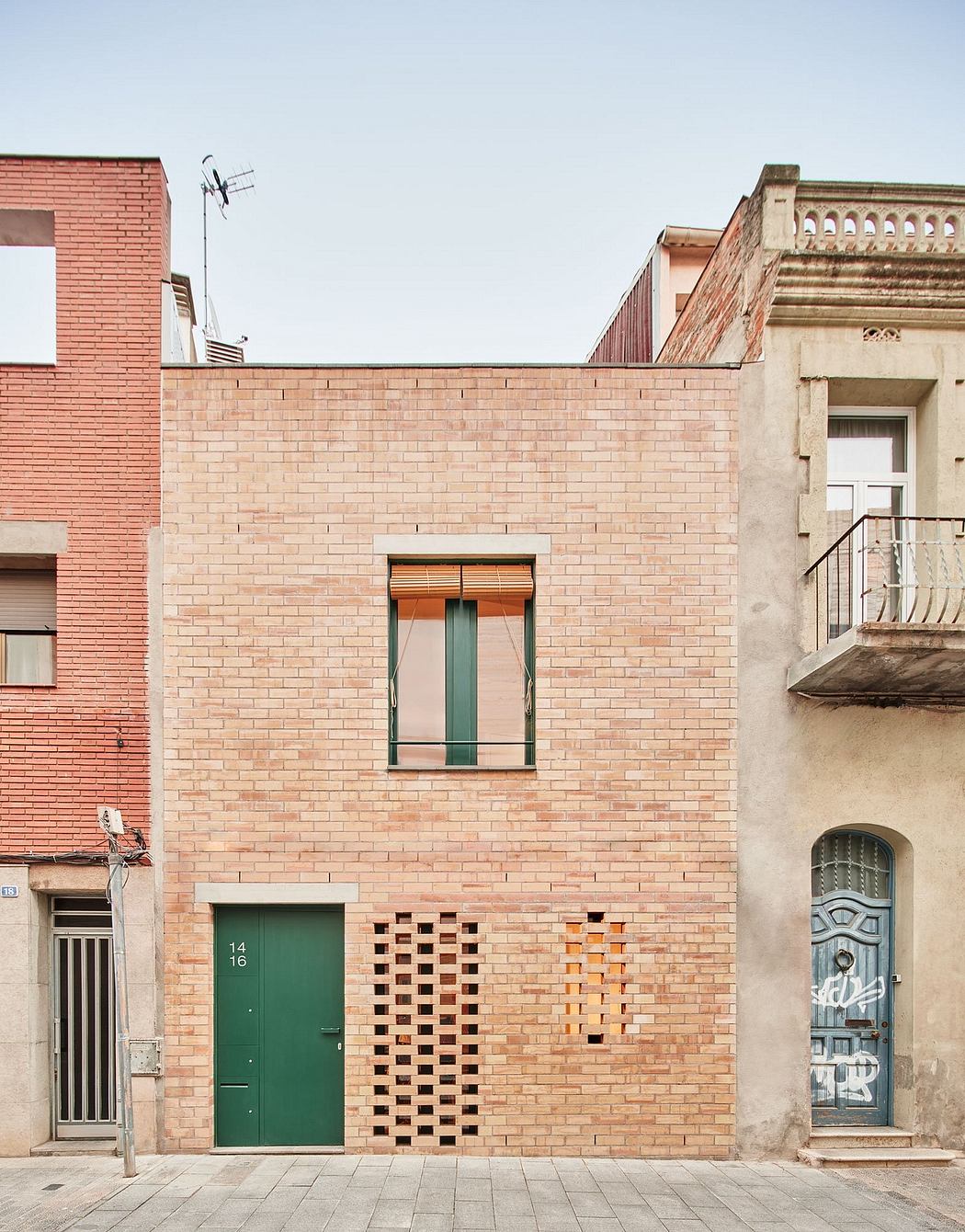 Detailed brick facade with recessed entryway and patterned openings, contrasting architectural styles.