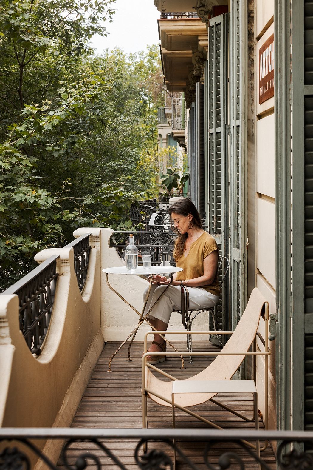 Cozy outdoor seating area on a balcony surrounded by lush greenery and rustic architecture.