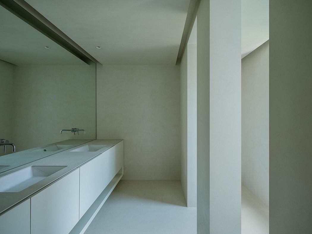 A sleek, minimalist bathroom with clean lines, a wall-mounted sink, and recessed lighting.