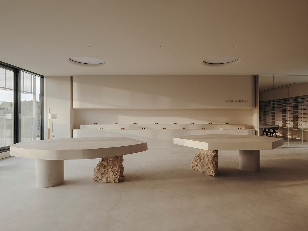 A minimalist interior with sculptural stone and concrete furnishings, large windows, and a sleek, modern aesthetic.