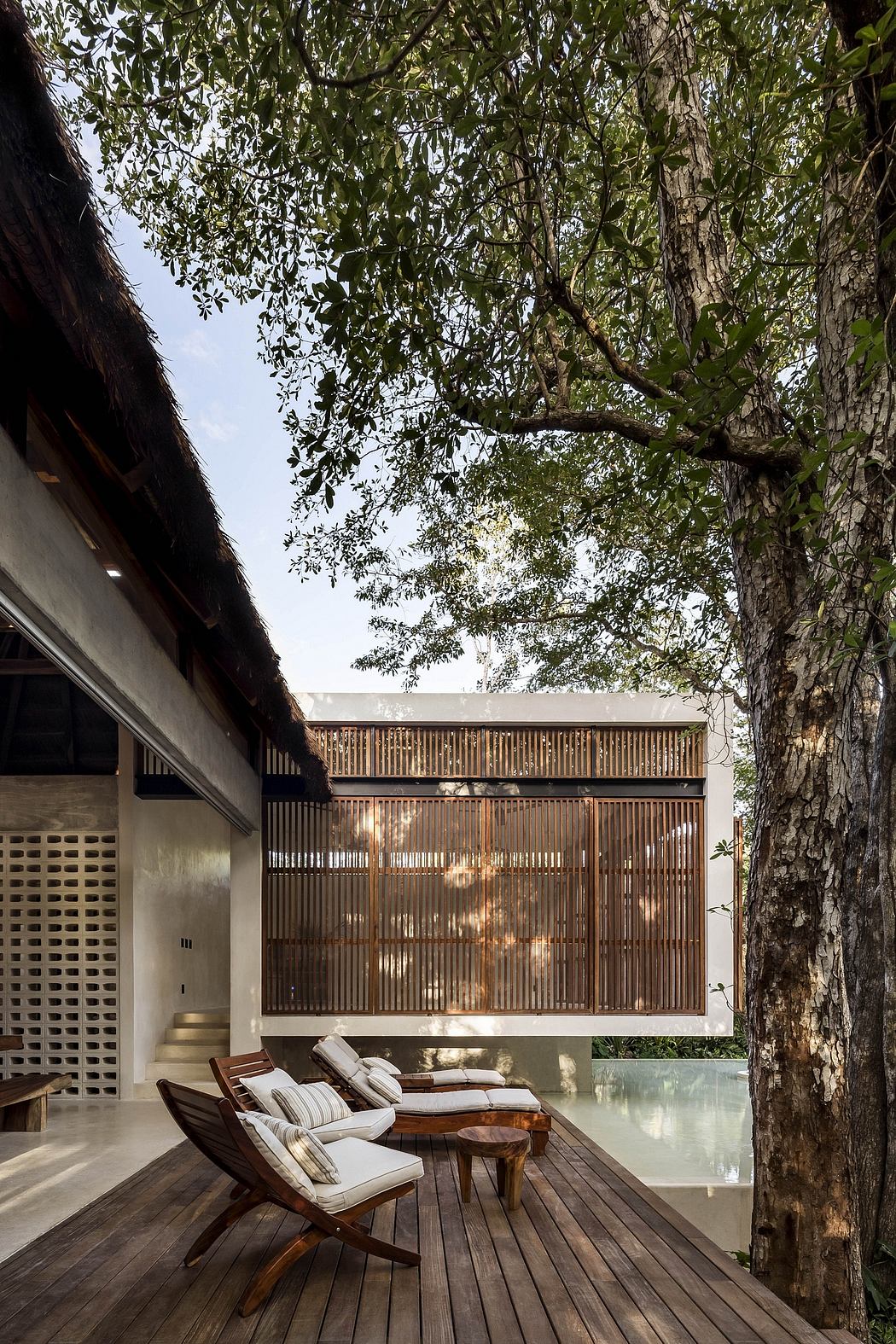A modern, wooden structure nestled among lush greenery, with a tranquil pool and seating area.