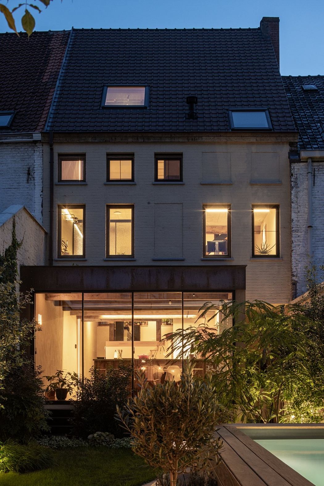 A multi-story residential building with a modern design, featuring large windows and a wooden deck.