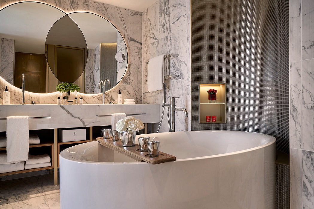 Luxurious bathroom with marble walls, circular mirror, and freestanding bathtub.