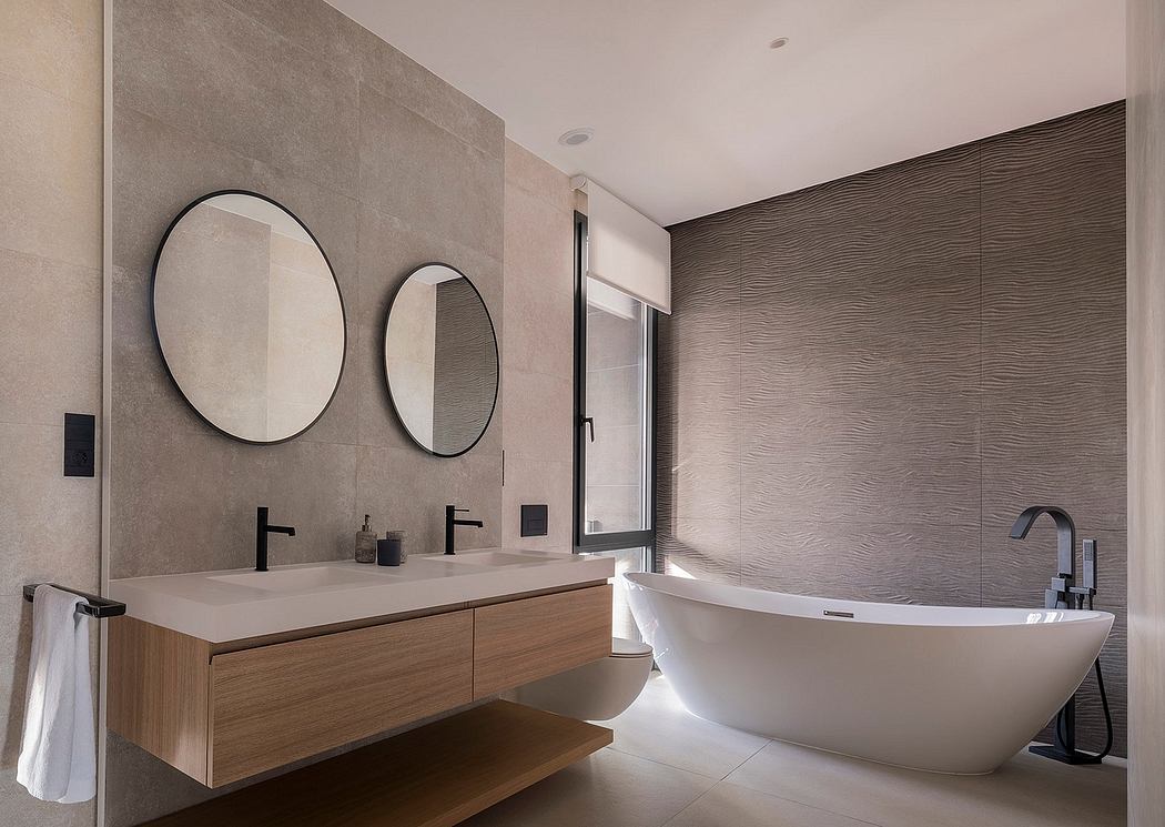 Minimalist bathroom with neutral palette, circular mirrors, and freestanding tub.