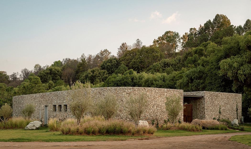 A stone building with a flat roof, surrounded by lush greenery and a well-manicured lawn.