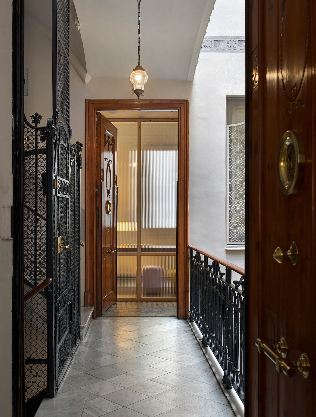 A grand entryway with ornate wooden doors, patterned tile flooring, and an ornate hanging light fixture.