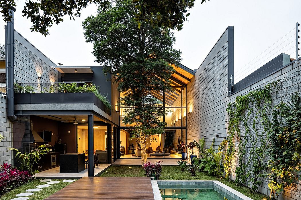 Modern architectural design with glass walls, wooden deck, and lush greenery surrounding a pool.
