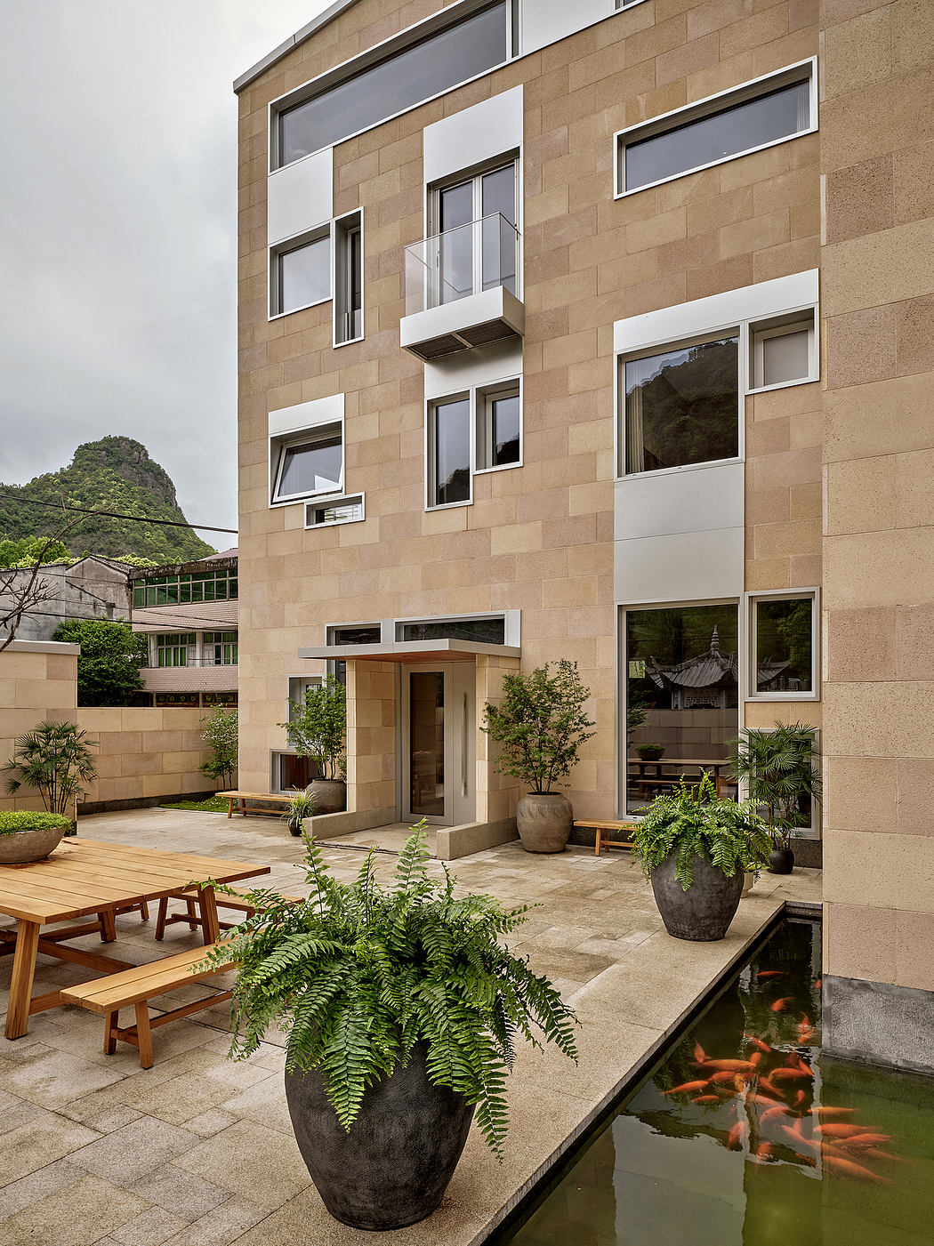 A modern, stone-clad building with a tranquil courtyard, featuring an ornamental pond and potted plants.