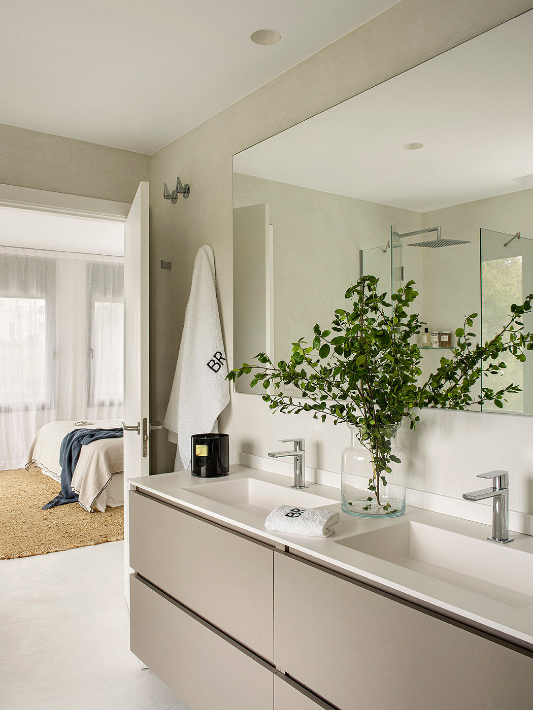 Minimalist bathroom with a vanity, large mirror, and a potted plant adding natural accents.