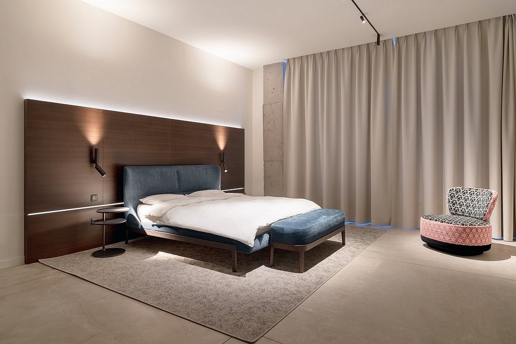 Spacious, modern bedroom with wooden paneling, plush carpet, and statement chair.